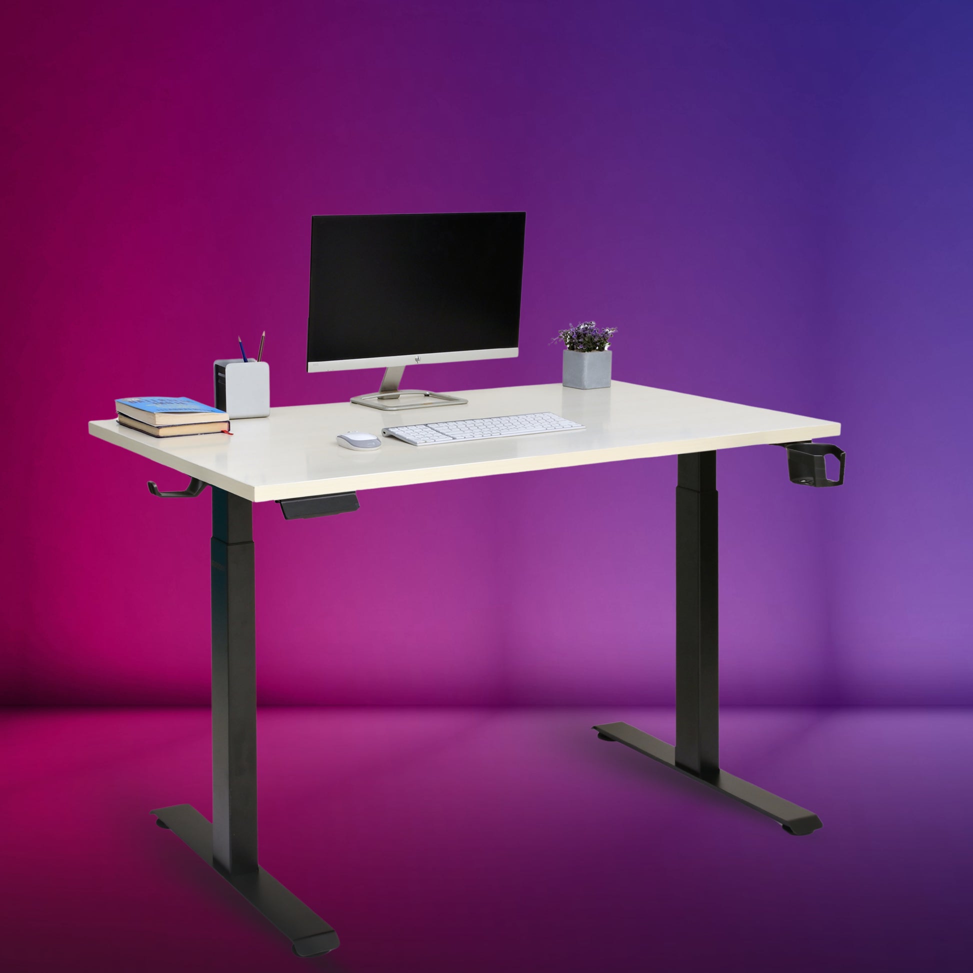 An adjustable standing desk with a brown tabletop, black telescopic frame, and dual motor mechanism, equipped with a computer monitor, stationery, and a potted plant on top.